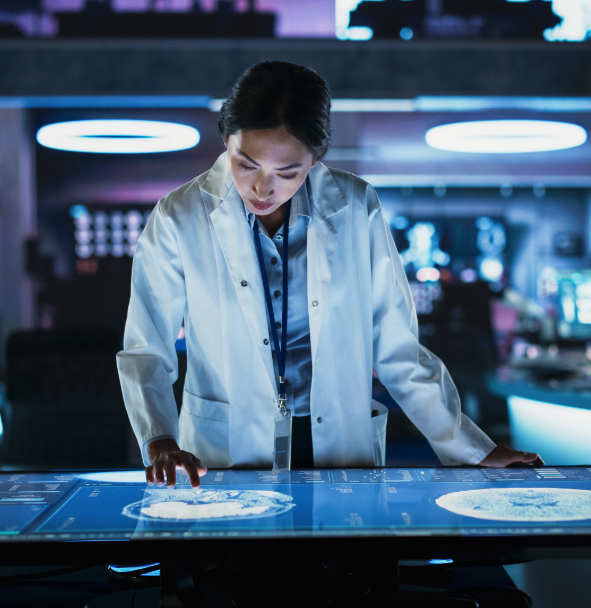 a person wearing a lab coat looking at a large monitor that shows images of a brain scan