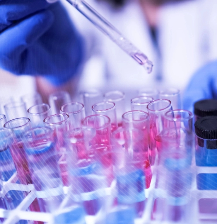 a person wearing a lab coat and gloves using a device to put a red liquid into vials